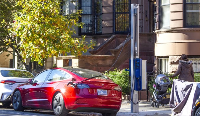 An electric car plugs into a FLO charger on a street in NYC.