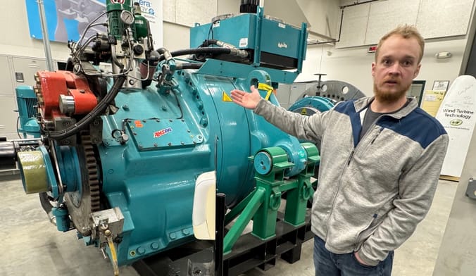 A person motions toward a large piece of machinery