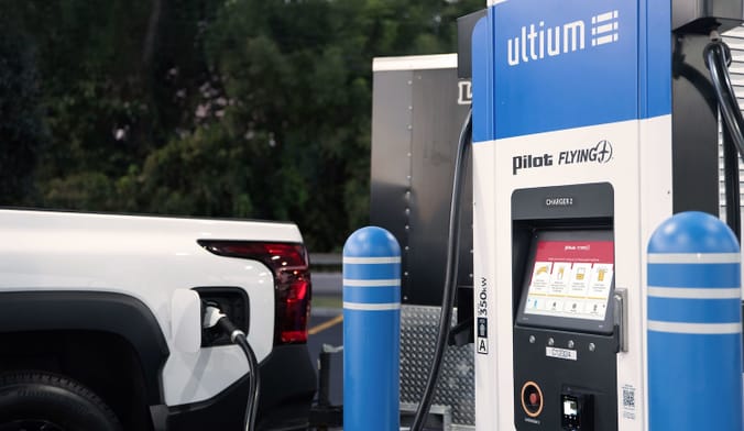 A car plugged into an EV charging station that reads "Ultium Pilot Flying"