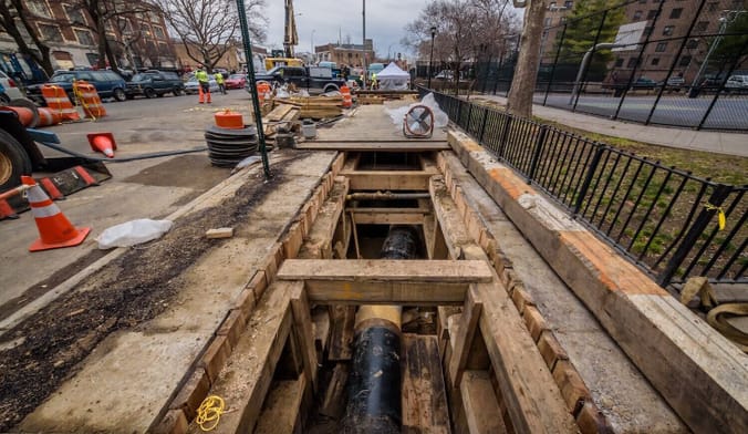A pipeline shown in an underground trench surrounded by a construction zone in a city