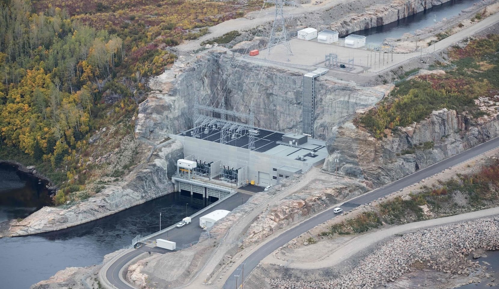 Roads leading to equipment and wires at a hydroelectric dam in a forest.