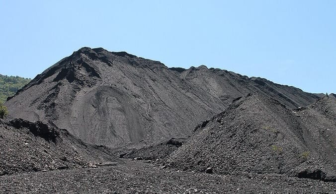 A pile of gray coal ash against a blue sky