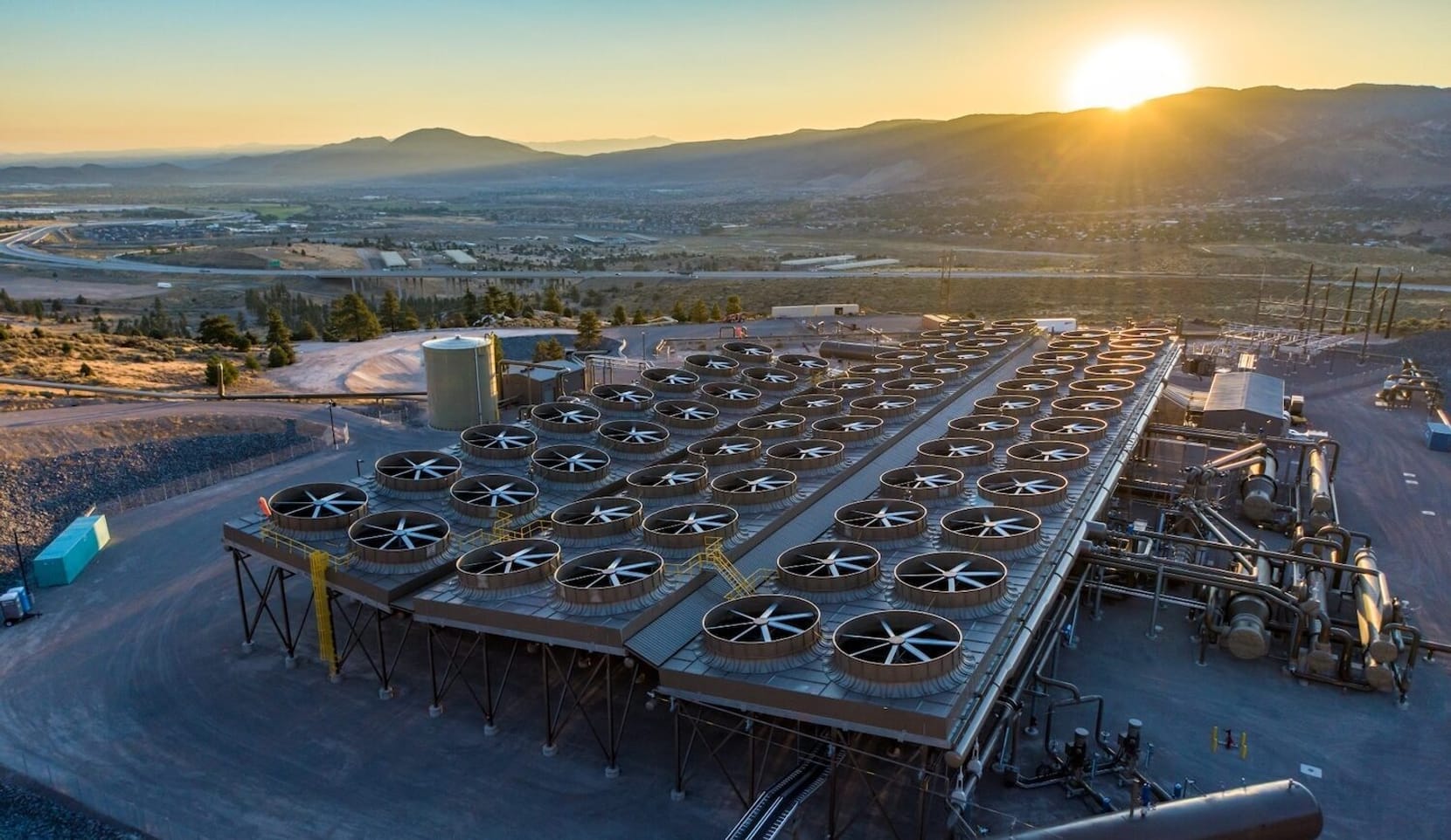 Aerial view of power plant at sunset backed by mountains