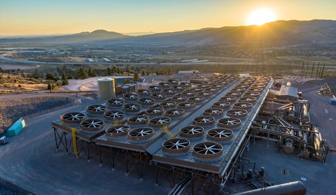 Aerial view of power plant at sunset backed by mountains