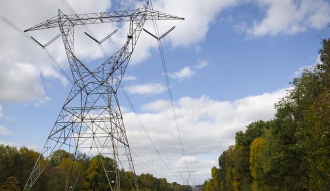 Transmission tower silhouetted against a blue cloudy sky.