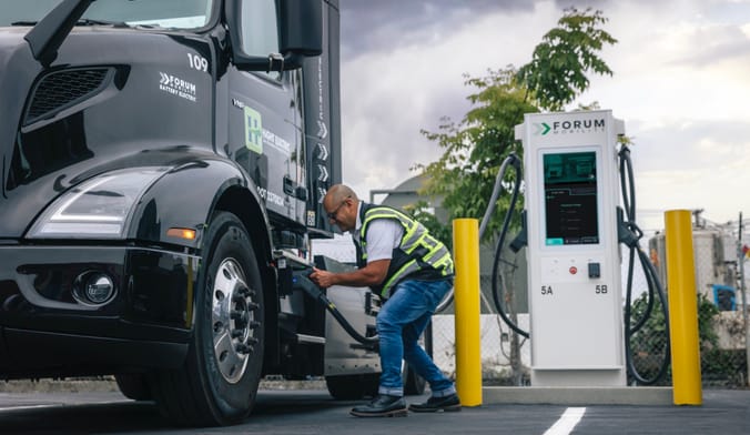 A driver plugs in an electric truck at a Forum Mobility charging depot at the Port of Long Beach.