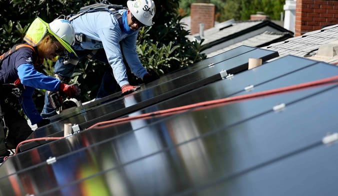 two men with solar panels on a house roof