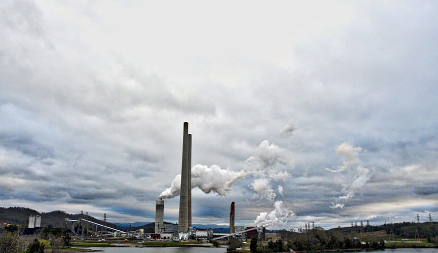 A large industrial facility silhouetted against a cloudy sky