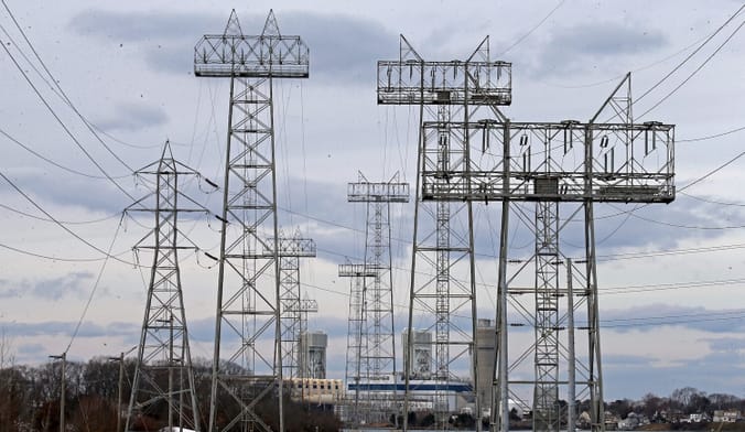 Power line towers silhouetted against a cloudy sky