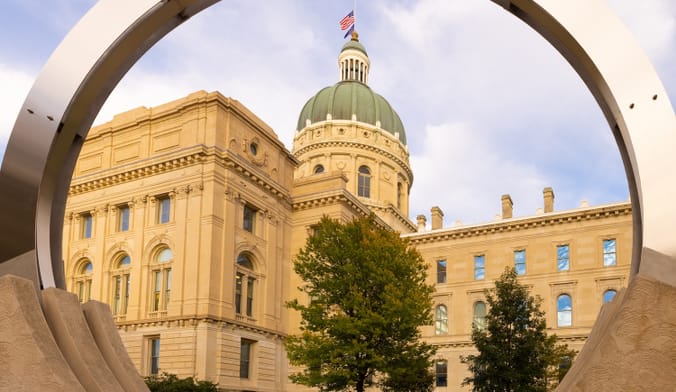 A large, ornately designed building with a domed top and U.S. flag on top, viewed through a circular sculpture.
