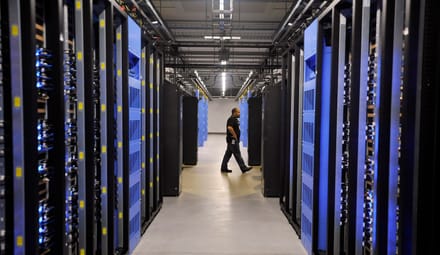 A person walks past rows of hardware in a warehouse