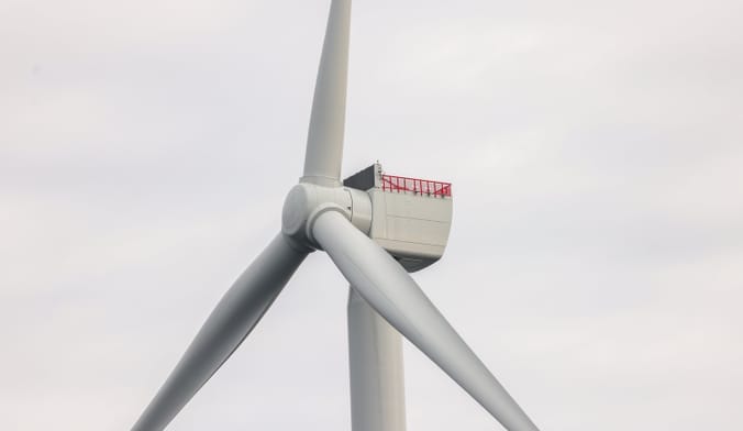 Close-up of top of wind turbine against a gray sky