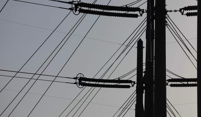 Silhouette of power line infrastructure against a gray sky