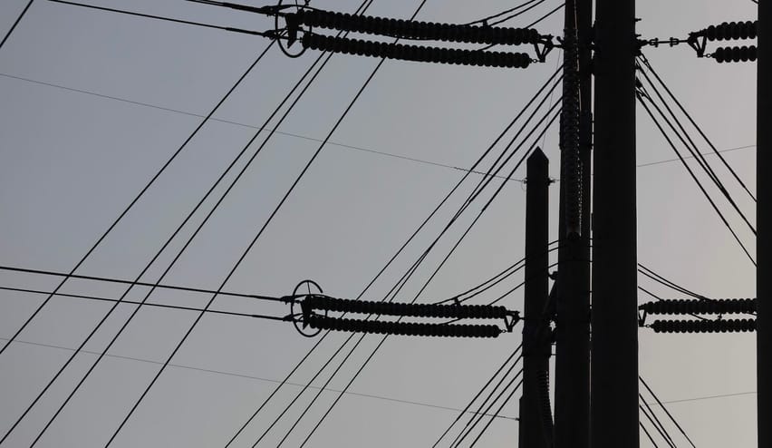 Silhouette of power line infrastructure against a gray sky