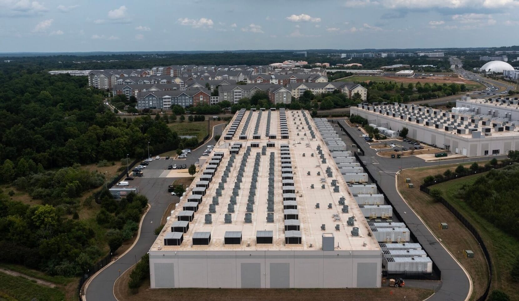 A large warehouse building surrounded by homes