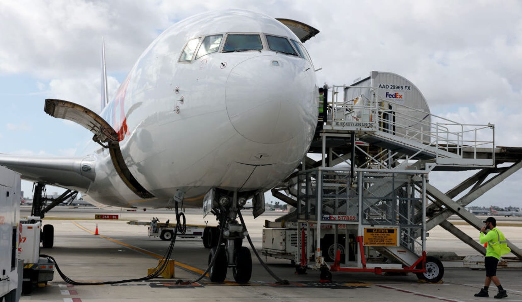 close up of front of cargo plane on runway being fueled and loaded.