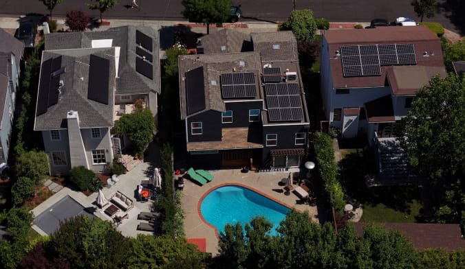 Aerial shot of three houses that all have solar panels on the roofs