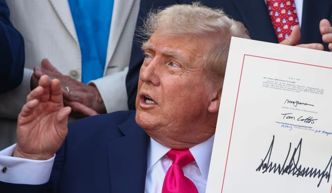 A person in a suit and tie holds up a document with signatures on it