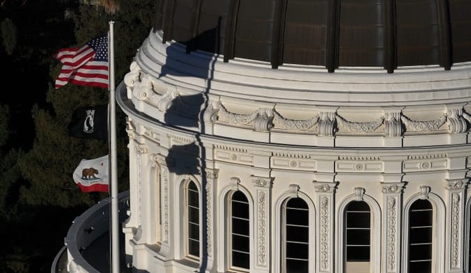 Government building with a domed top. Three flags fly on a pole on the building.