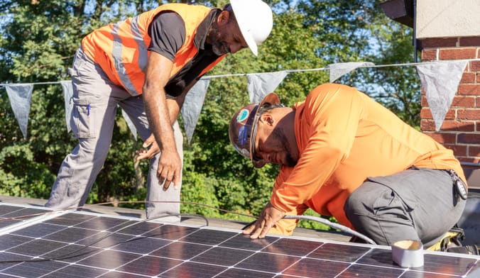 Workers installing rooftop solar panels