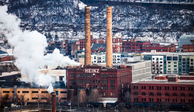 A factory with the word "Heinz" painted on the front is located in a snowy city.