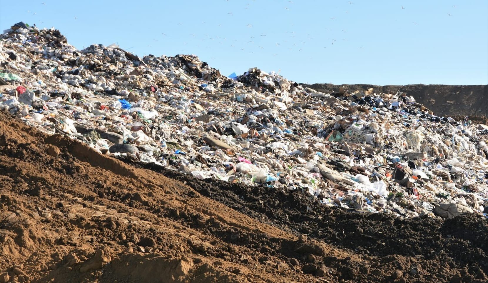 Piles of trash and dirt outside in a landfill.