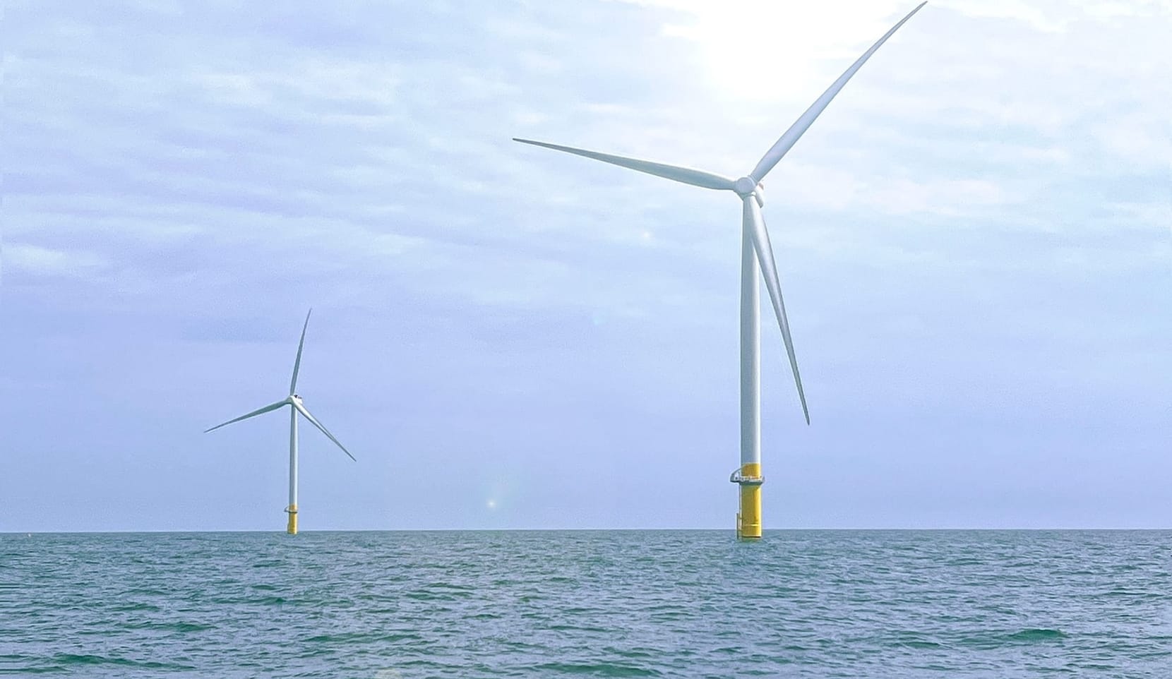 Wind turbines rise from the sea on a sunny day