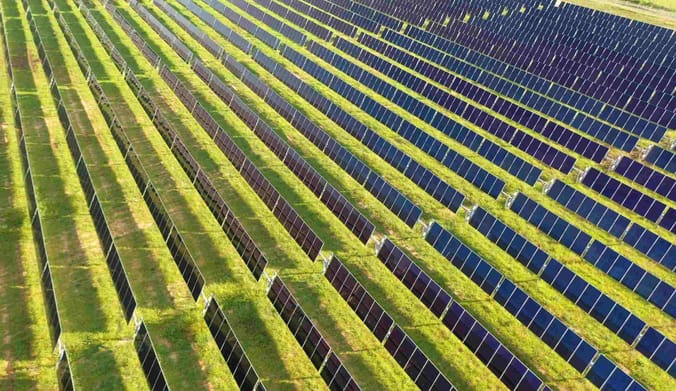 Aerial view of rows of utility-scale green solar in a field