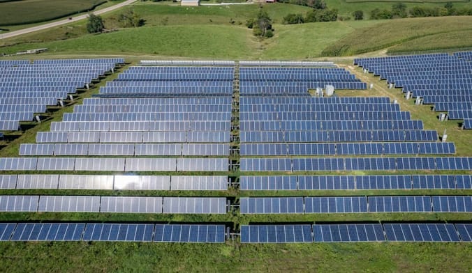 Aerial shot of rows of solar panels on grassy field