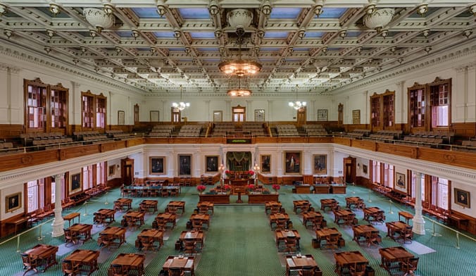 A large, ornately decorated, empty room filled with wooden tables and chairs.